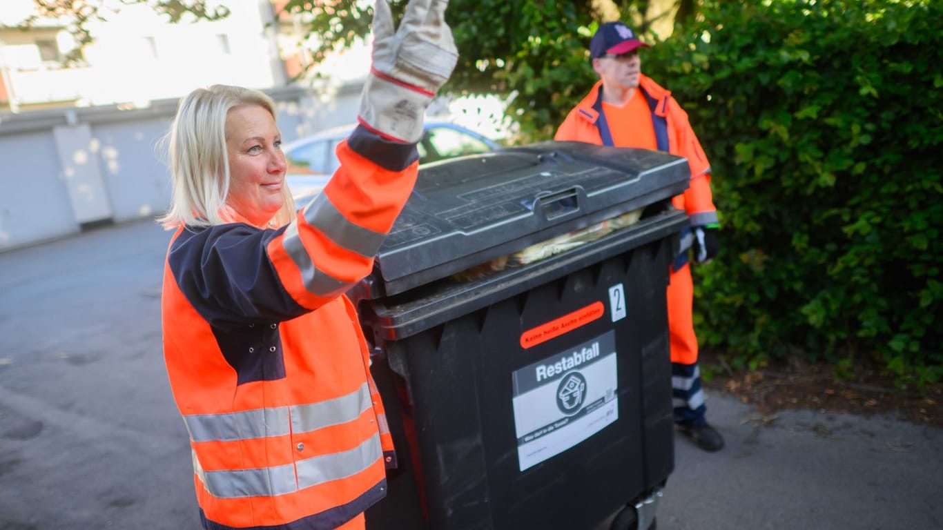 Yvonne Pedd weist per Handzeichen ein Müllfahrzeug bei der Abholung von Restmüll ein.