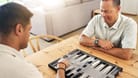 Senior, man and play backgammon in home with focus, strategy and contest for thinking, moving or son by table. Elderly man, board game competition and relax with bonding, love and family house lounge