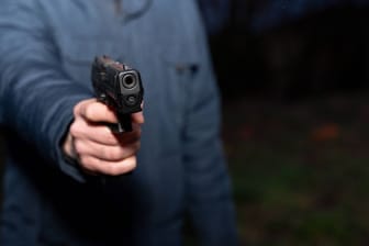 Germany - December 31, 2023: Man aims a pistol in the dark *** Mann zielt bei Dunkelheit mit einer Pistole