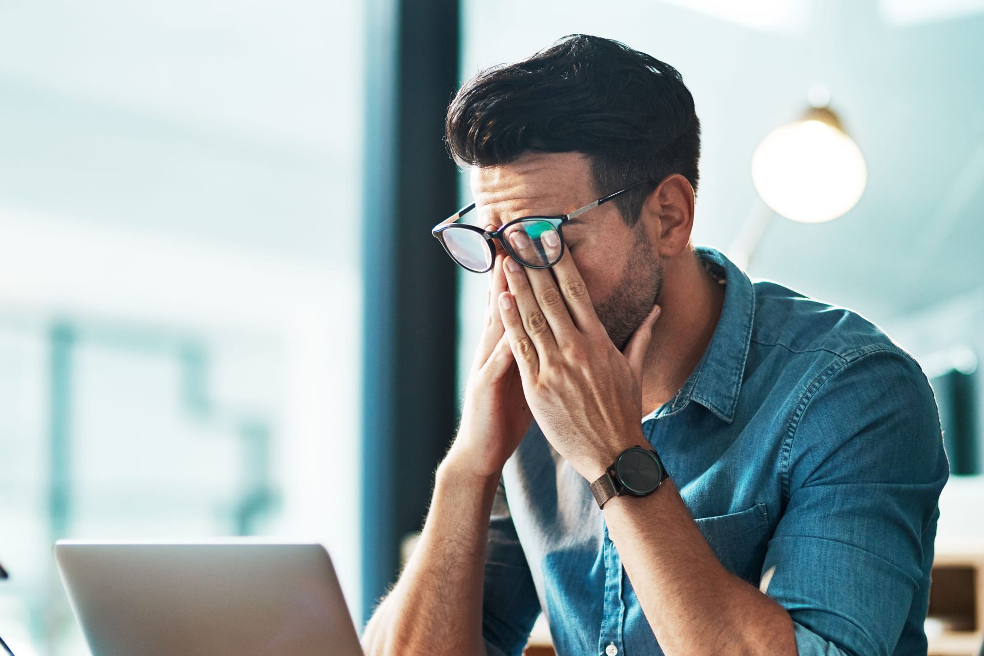 Mann am Computerarbeitsplatz reibt sich die Augen