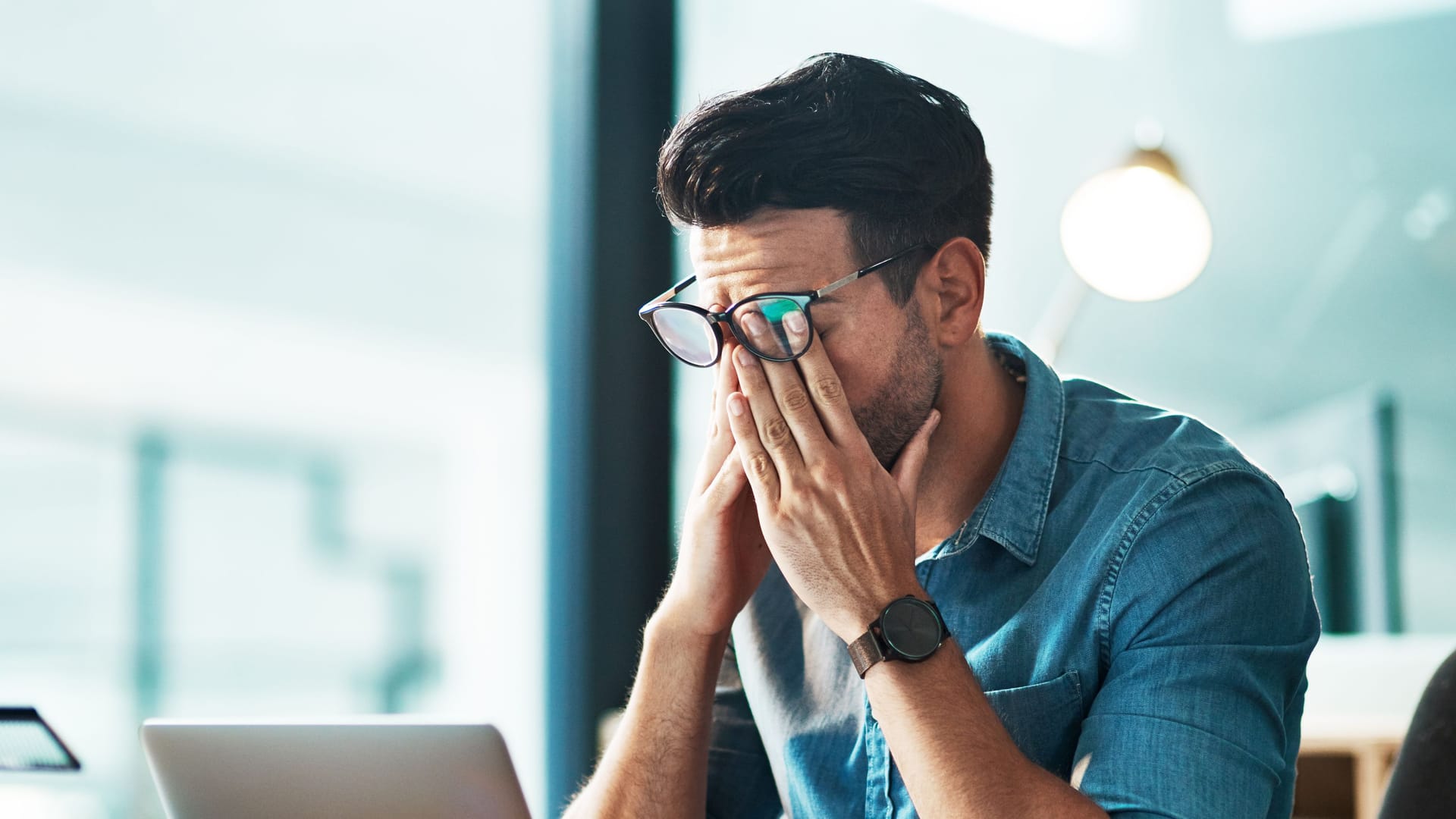 Mann am Computerarbeitsplatz reibt sich die Augen