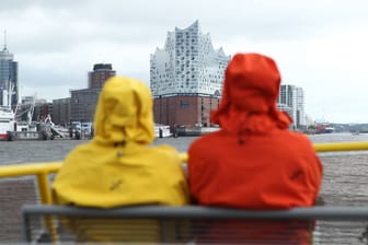 Eine Frau und ein Mann sind mit Regenjacken an Deck einer HADAG-Fähre (Symbolfoto): Das Wetter in Hamburg und Schleswig-Holstein bleibt durchwachsen.