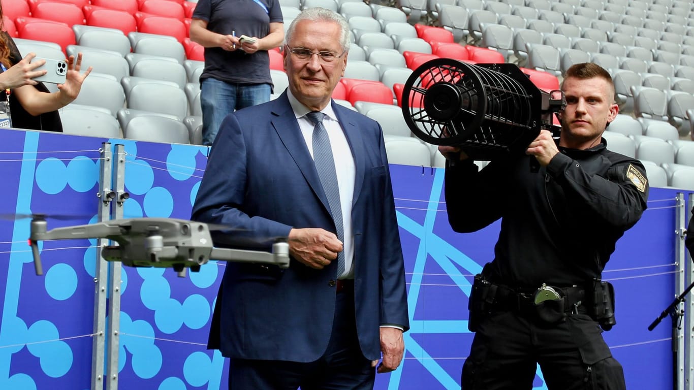 Bayerns Innenminister Joachim Herrmann (CSU) beobachtet, wie ein Polizist eine Drohne ins Visier nimmt.