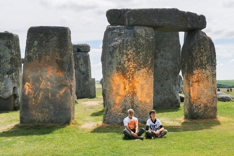 Demonstranten von "Just Stop Oil" sitzen vor dem Steinmonument Stonehenge: Aktivisten der Grupe besprühten die Steine zuvor mit Farbe.