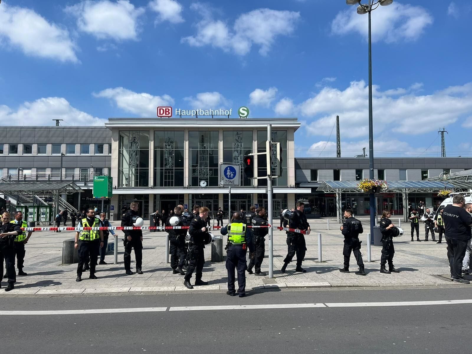 Die Polizei bringt Absperrband vor dem Bahnhofsvorplatz an.