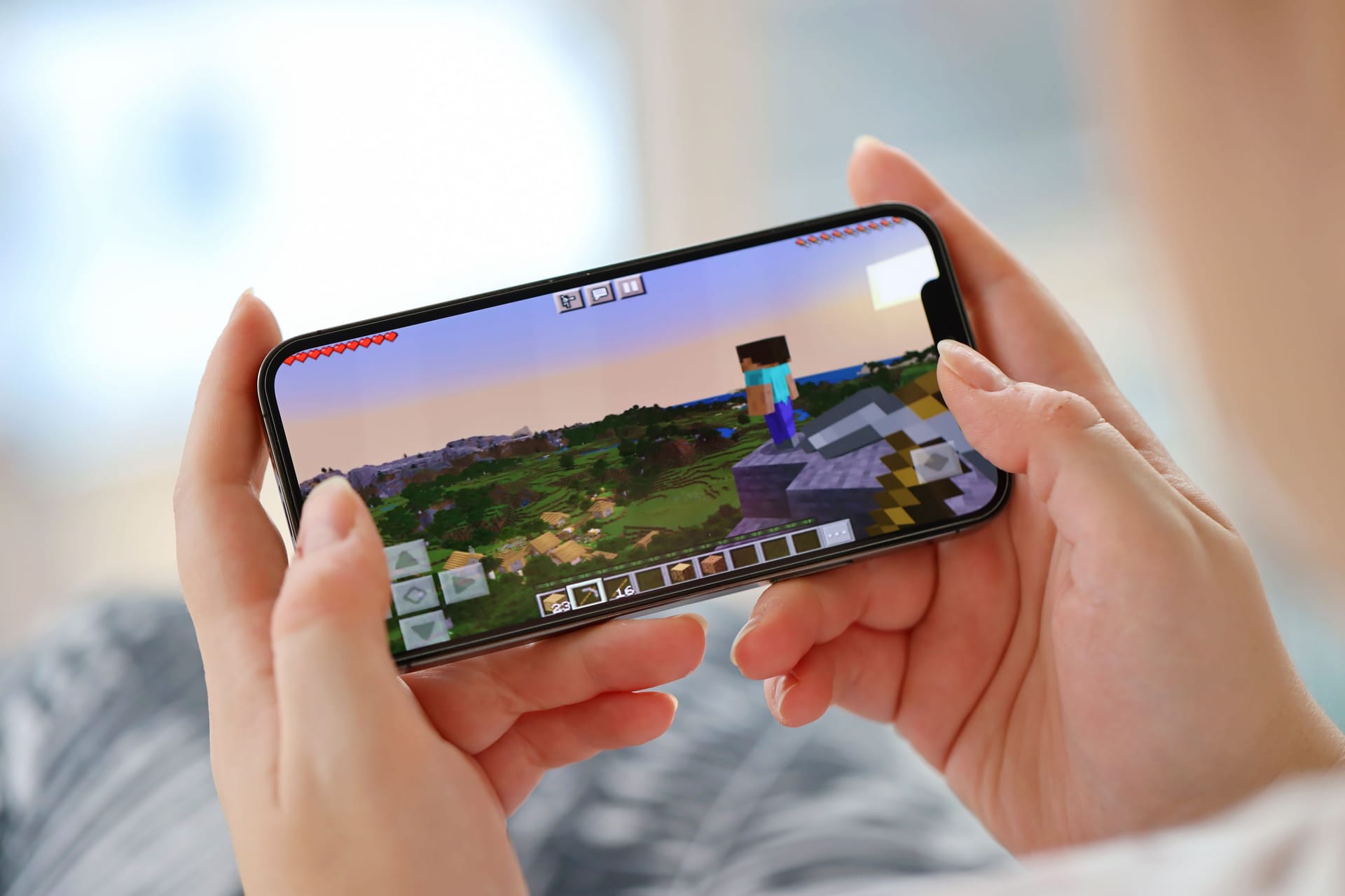 Minecraft mobile iOS game on iPhone 15 smartphone screen in female hands during mobile gameplay