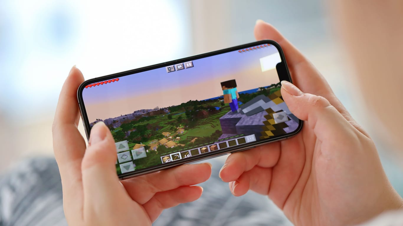 Minecraft mobile iOS game on iPhone 15 smartphone screen in female hands during mobile gameplay