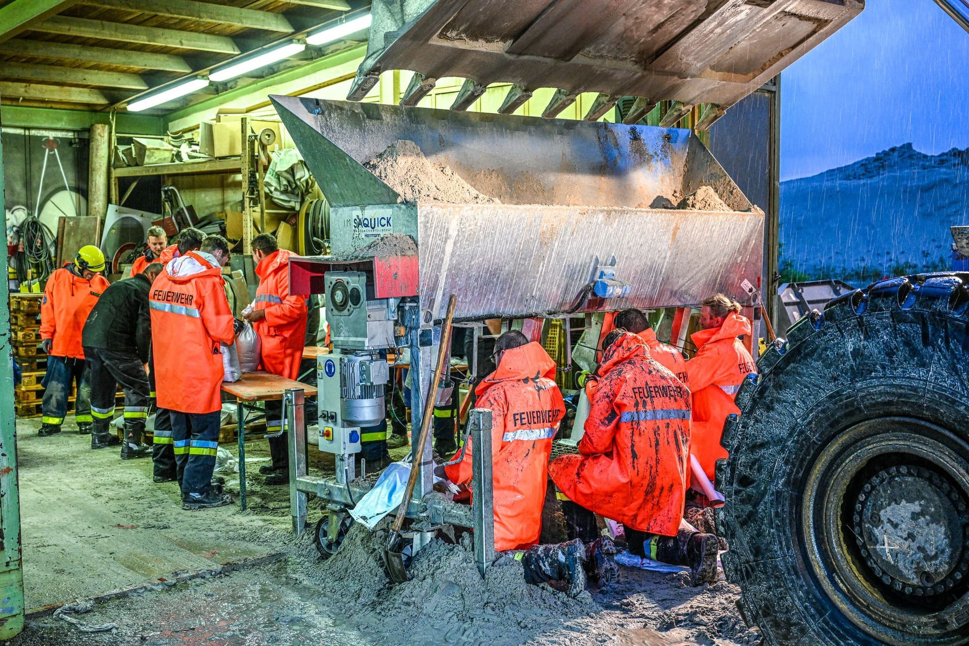 Einsatzkräfte der Feuerwehr und von dem Technisches Hilfswerk (THW) befüllen Sandsäcke in Thannhausen (Bayern).