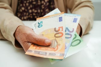 Rentnerin hält Geldscheine: Zusätzlich zur Rentenerhöhung gewährt der Staat diesen Juli einigen Rentnern noch einen Zuschlag.