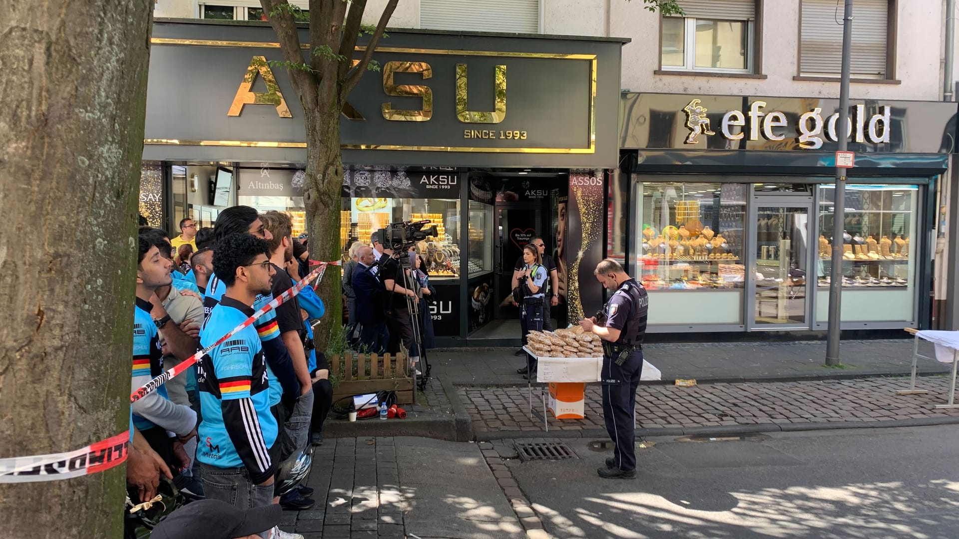 Besucher hinter einem Absperrband auf der Keupstraße: Die Polizei ist mit Spürhunden im Einsatz.