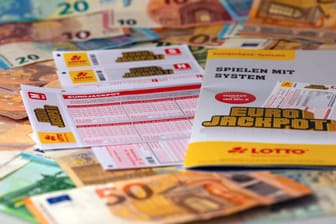 Geldscheine liegen neben einem Eurojackpot-Spielschein (Symbolfoto): In Bayern haben am Dienstag zwei Spieler große Summen gewonnen.
