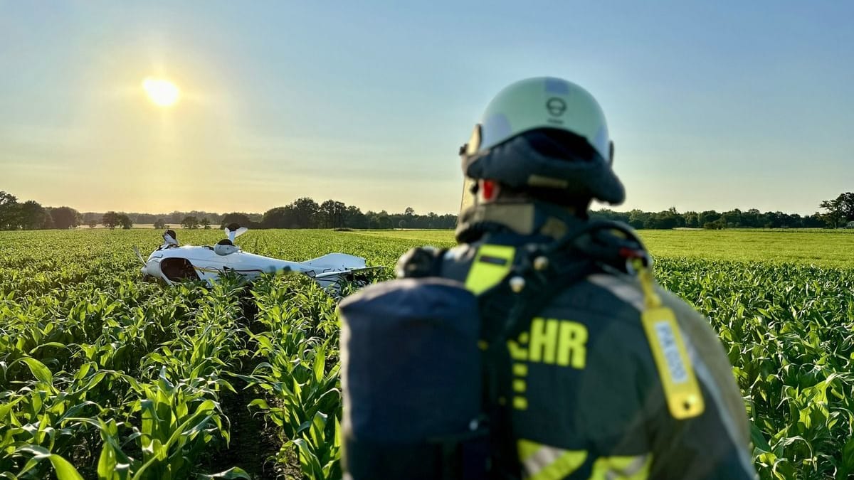 Ein Feuerwehrmann auf einem Acker in Hünxe: Das Flugzeug vor ihm landete kopfüber auf dem Feld.