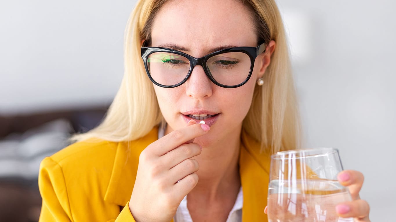 Frau will Tablette mit Wasser einnehmen