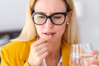 Frau will Tablette mit Wasser einnehmen