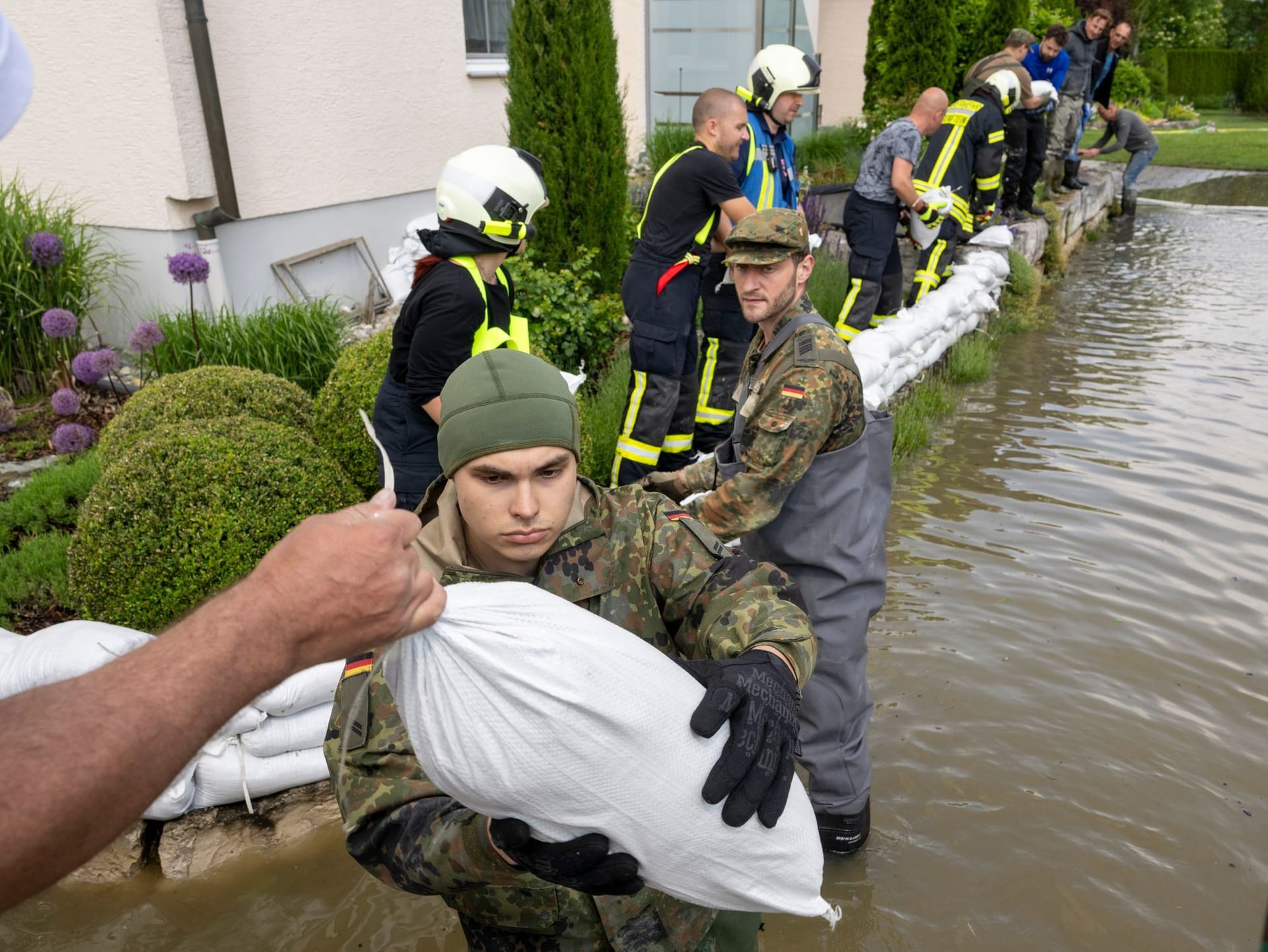 Bayern, Gundelfingen: Soldaten der Bundeswehr errichten gemeinsam mit zivilen Feuerwehrkräften eine Barriere aus Sandsäcken.