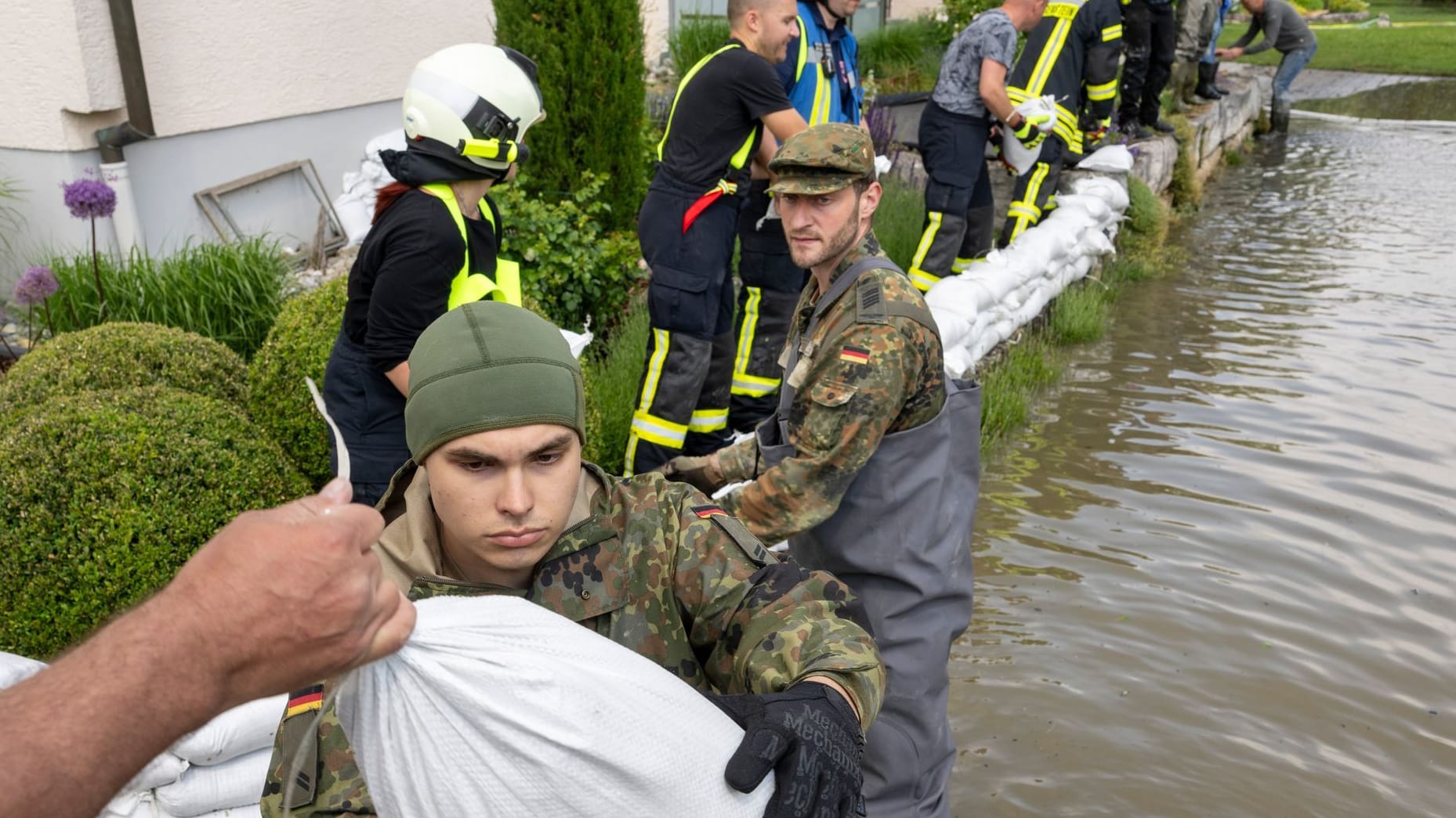 Bayern, Gundelfingen: Soldaten der Bundeswehr errichten gemeinsam mit zivilen Feuerwehrkräften eine Barriere aus Sandsäcken.