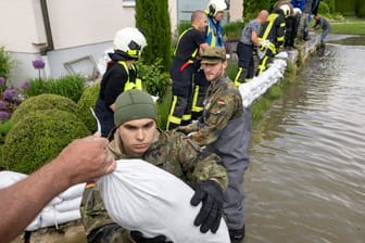 Bayern, Gundelfingen: Soldaten der Bundeswehr errichten gemeinsam mit zivilen Feuerwehrkräften eine Barriere aus Sandsäcken.