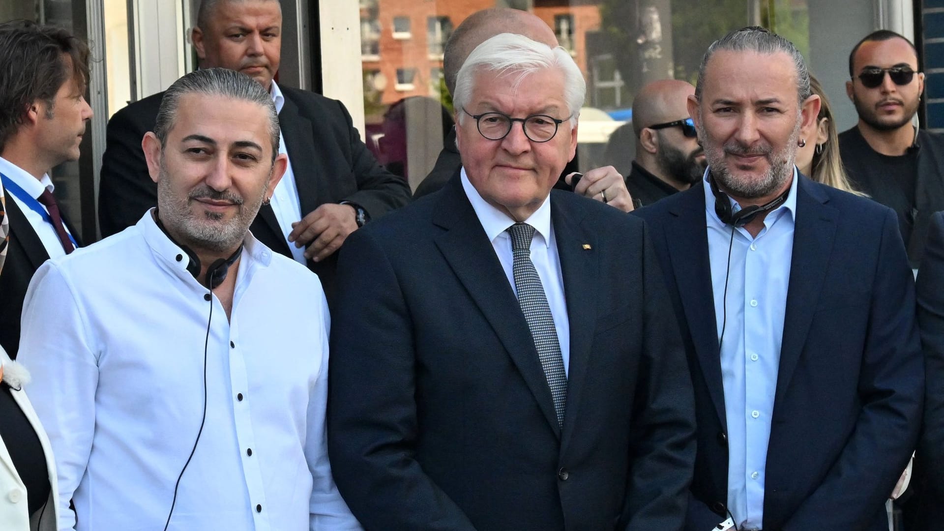 Bundespräsident Frank-Walter Steinmeier (Mitte) steht mit Hasan Yildirim (links) und Özcan Yildirim (rechts) vor ihrem Friseurgeschäft, vor dem vor 20 Jahren die NSU-Nagelbombe hochging.