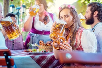 Woman in Tracht looking into camera while drinking a mass of beer