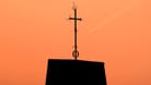 Ein Kreuz steht auf dem Dach einer Kirche vor Abendhimmel (Symbolbild): Die Vorfälle waren durch eine Anzeige der evangelischen Kirche in Bremen bekanntgeworden.