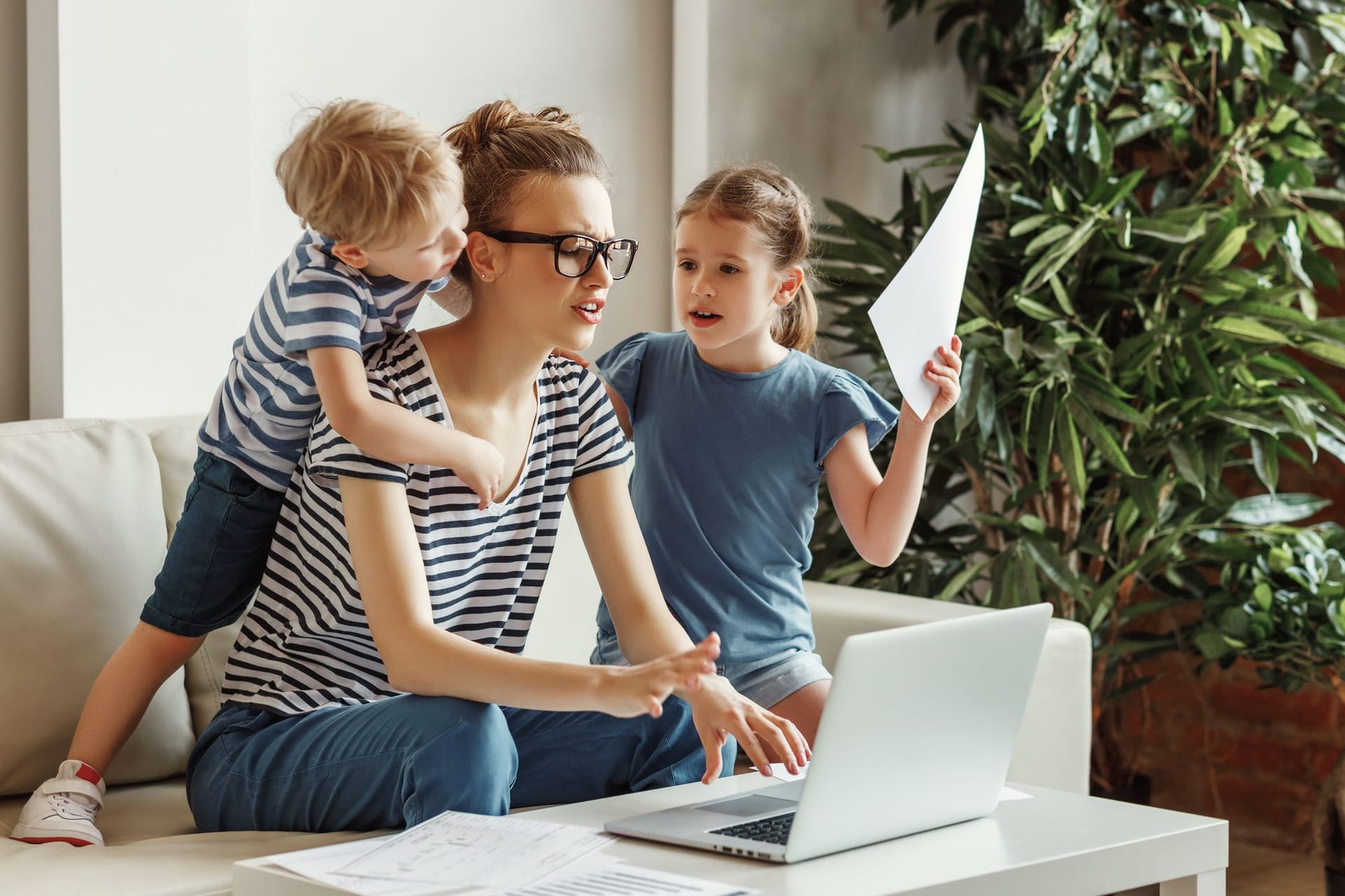 Mutter mit zwei Kindern arbeitet an einem Laptop