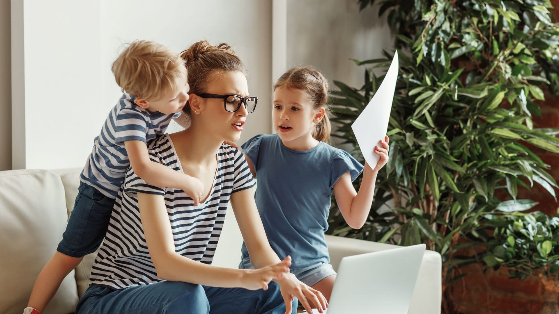 Mutter mit zwei Kindern arbeitet an einem Laptop