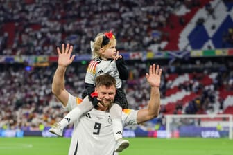Niclas Füllkrug trägt nach dem Sieg seine Tochter Emilia durch das Stadion.