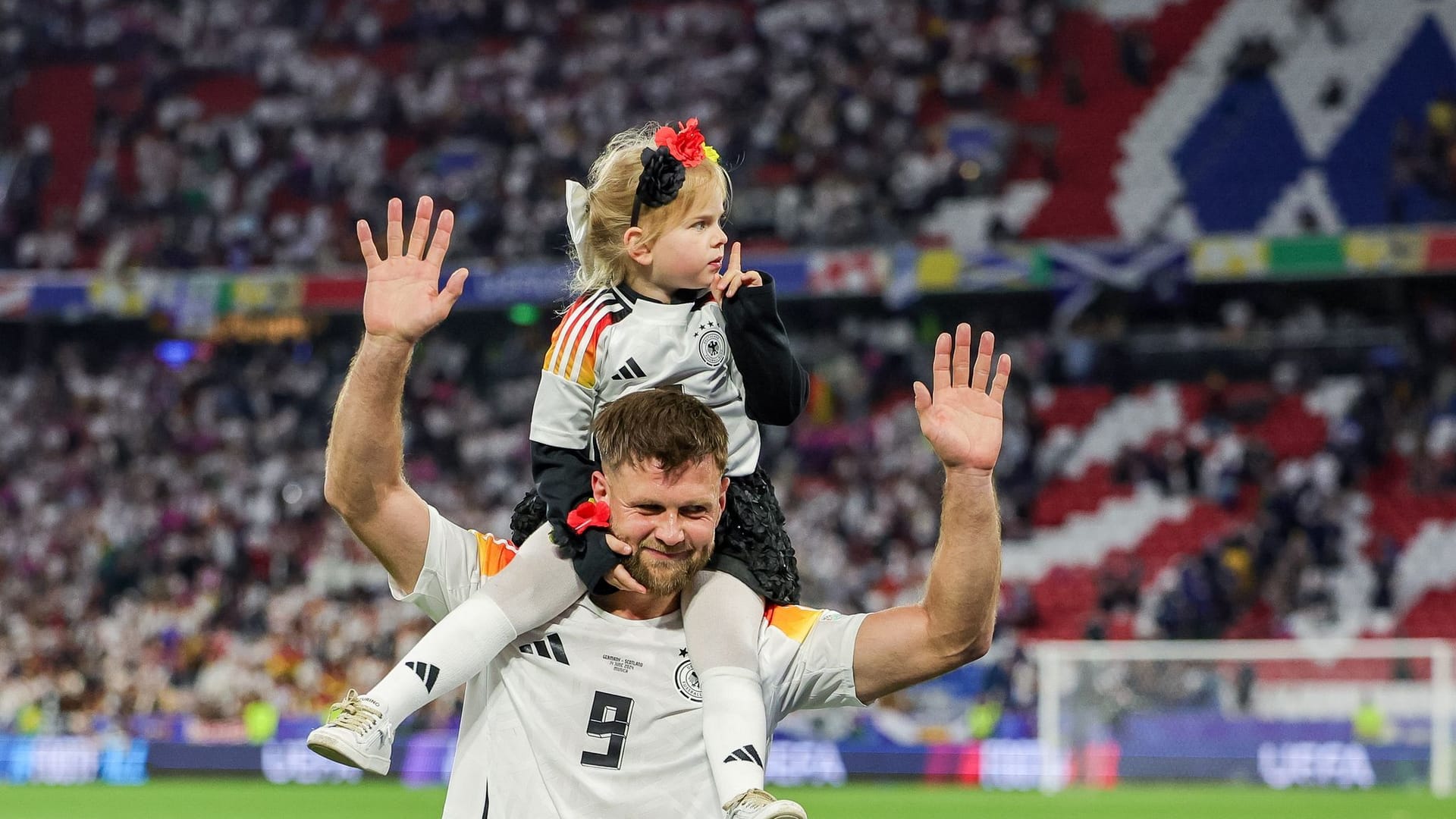 Niclas Füllkrug trägt nach dem Sieg seine Tochter Emilia durch das Stadion.