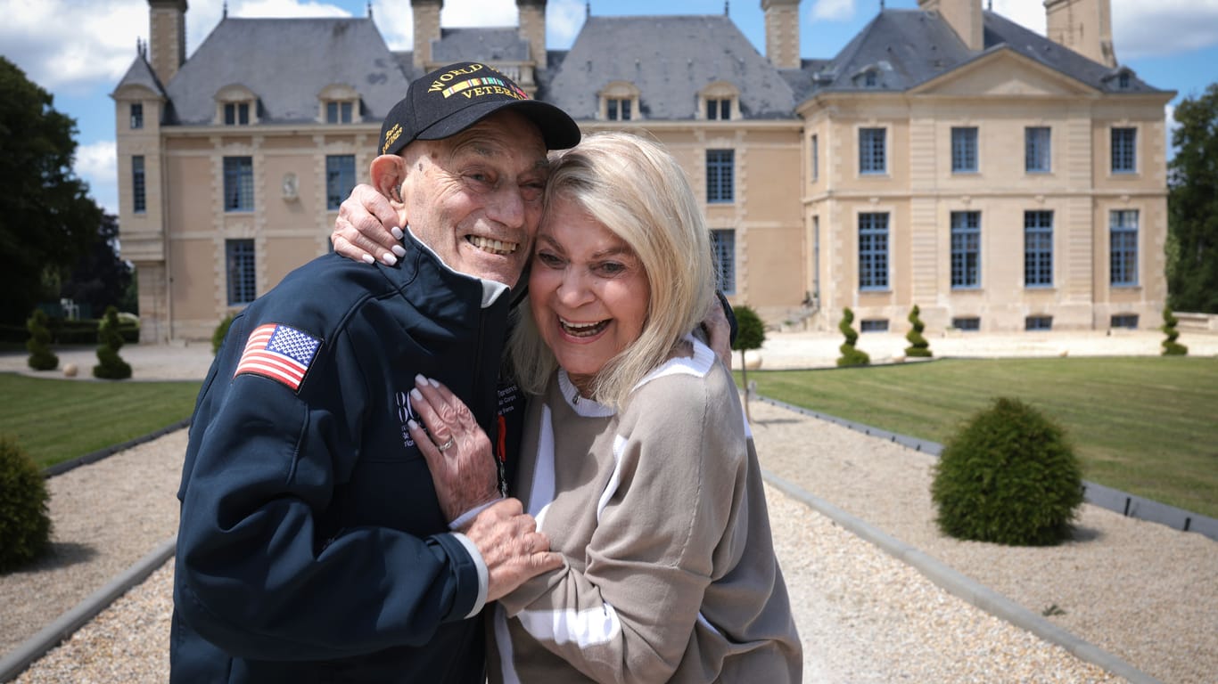Der 100-jährige Harold Terens steht mit seiner Frau, der 96-jährigen Jeanne Swerlin, vor dem Rathaus von Villers-Bocage.