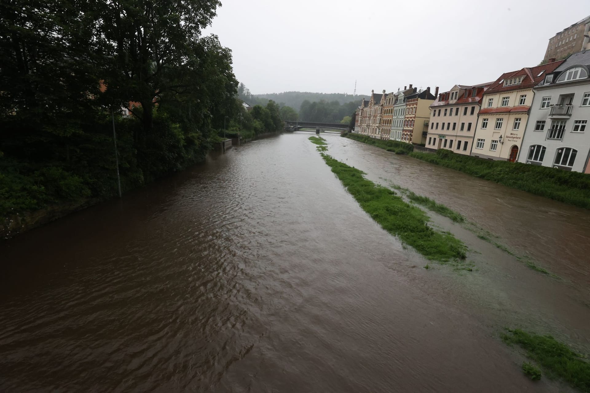 Thüringen, Greiz: Ein Parkplatz (links) am Ufer des Flusses "Weiße Elster" ist vollständig überflutet.