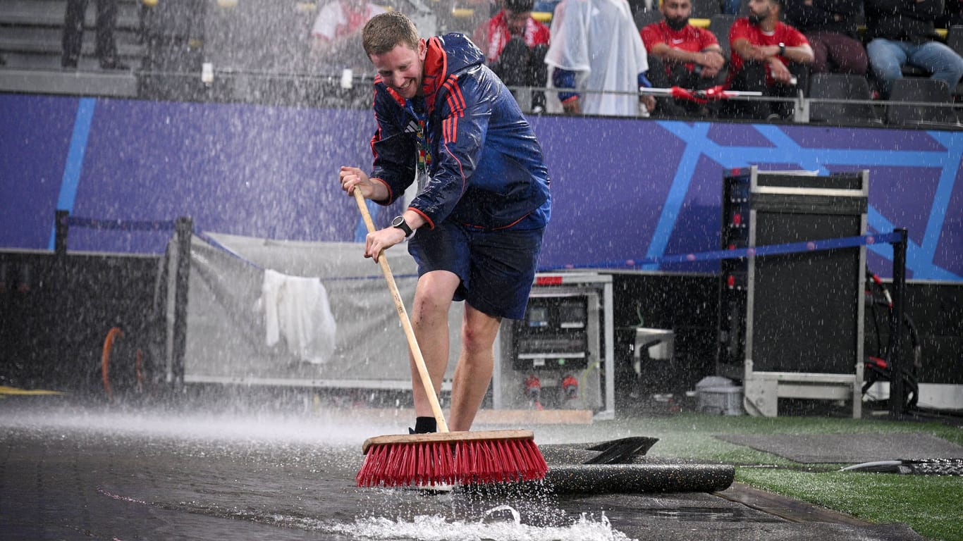 Mit Besen gegen das Wasser: Starke Regenfälle sorgen im Dortmunder Stadion für chaotische Zustände.