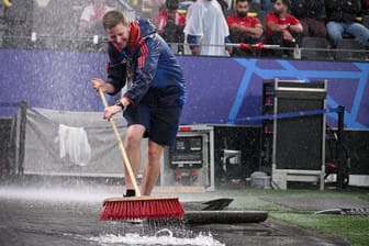 Mit Besen gegen das Wasser: Starke Regenfälle sorgen im Dortmunder Stadion für chaotische Zustände.