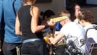 Eine Kellnerin trägt Speisen und Getränke an einem Tisch im Außenbereich eines Restaurants (Symbolfoto): Ein Restaurants in Ottensen kämpft um seine Außenterrasse.