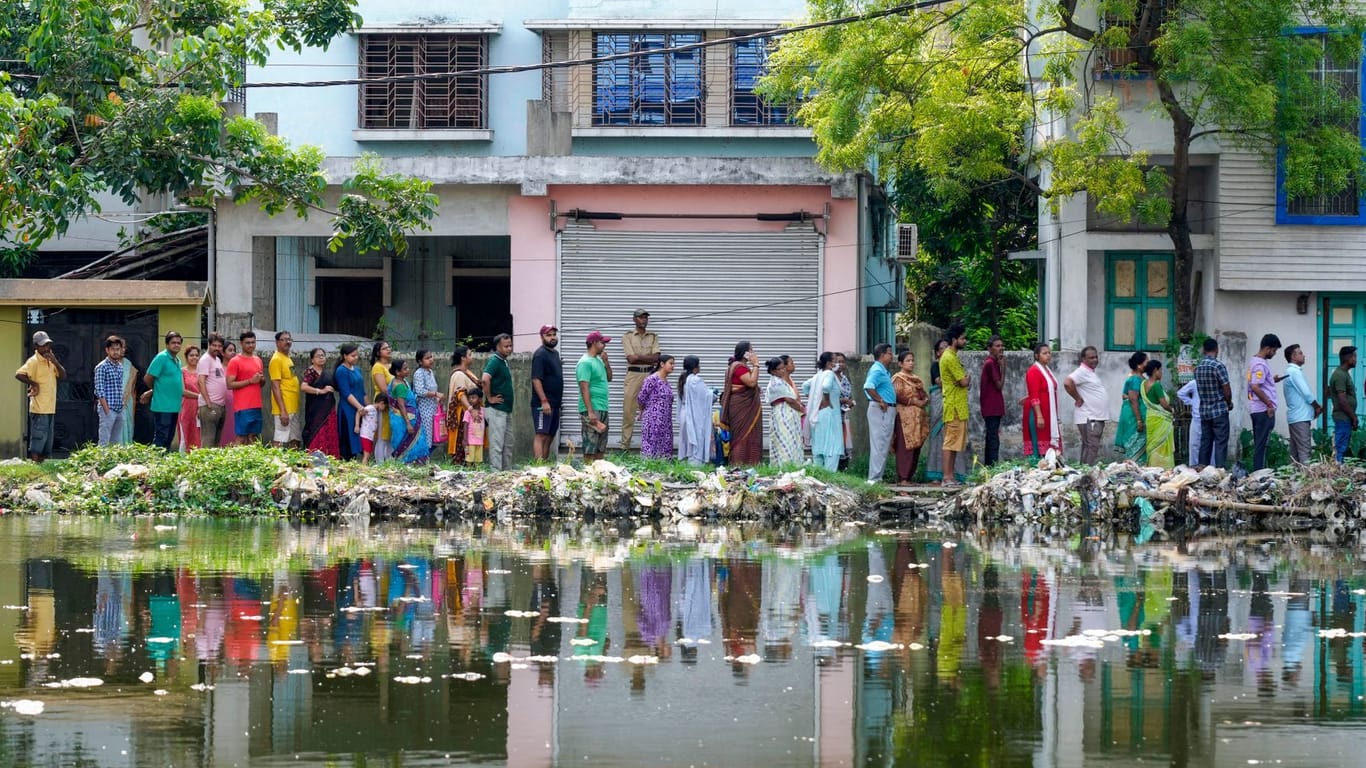 Indien, Howrah: Menschen stehen bei bis zu 40 Grad in einer Schlange an, um vor einer Wahlkabine während der fünften Runde der mehrstufigen nationalen Wahlen zu wählen.