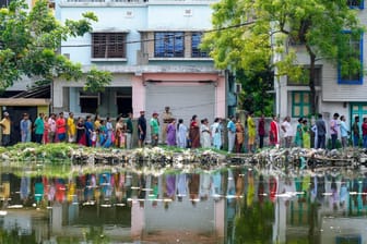 Indien, Howrah: Menschen stehen bei bis zu 40 Grad in einer Schlange an, um vor einer Wahlkabine während der fünften Runde der mehrstufigen nationalen Wahlen zu wählen.