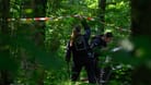 Eine Polizistin hält in einem Wald Absperrband hoch. Hier wurde die Leiche der neunjährigen Valeriia gefunden.