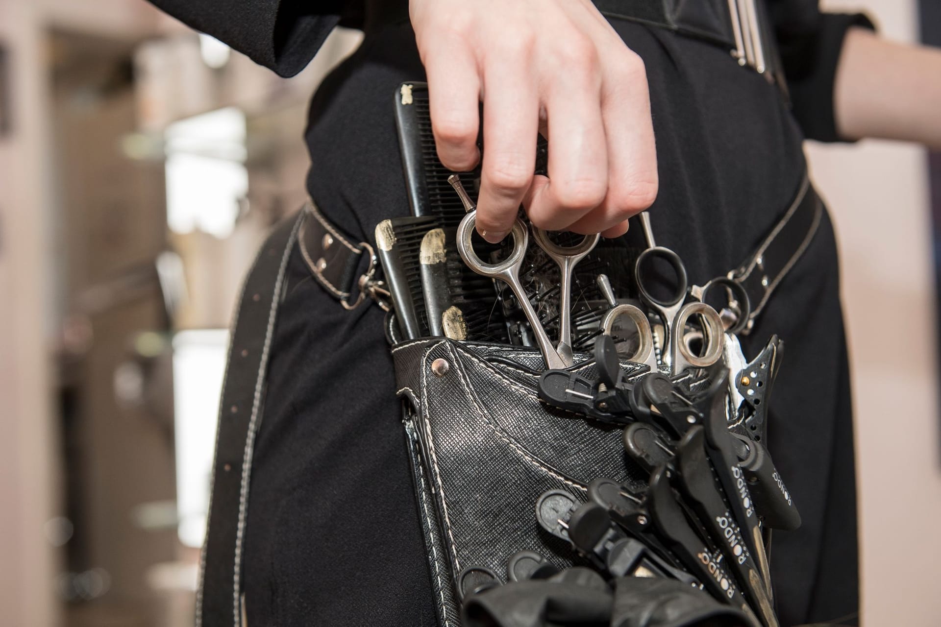 Eine Friseurin zieht eine Schere aus ihrer Friseur-werkzeugtasche