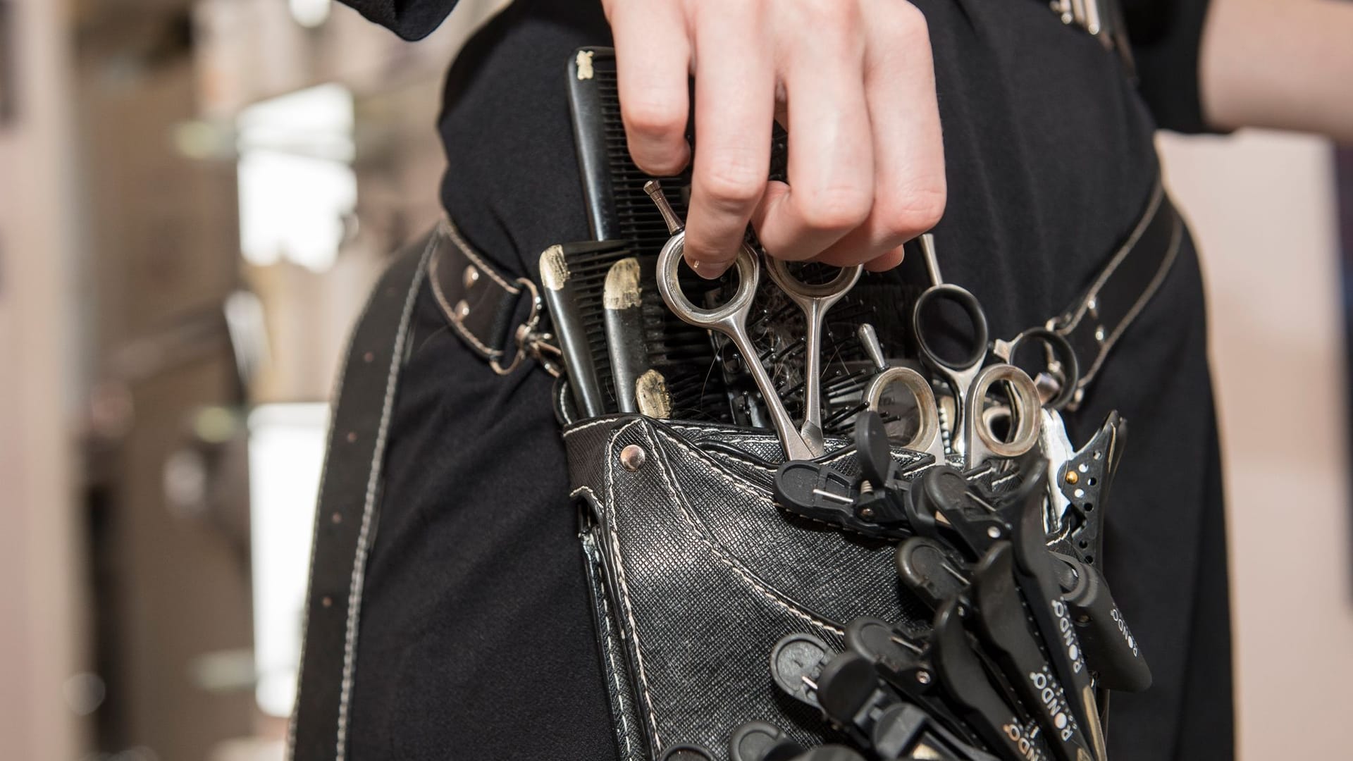 Eine Friseurin zieht eine Schere aus ihrer Friseur-werkzeugtasche