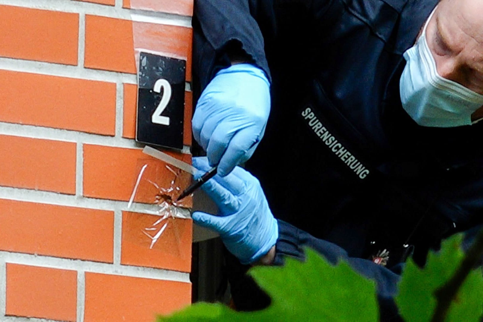Ein Beamter untersucht ein Einschussloch neben einem Balkon: Noch ist unklar, wer wie oft und mit welchen Waffen geschossen hat.
