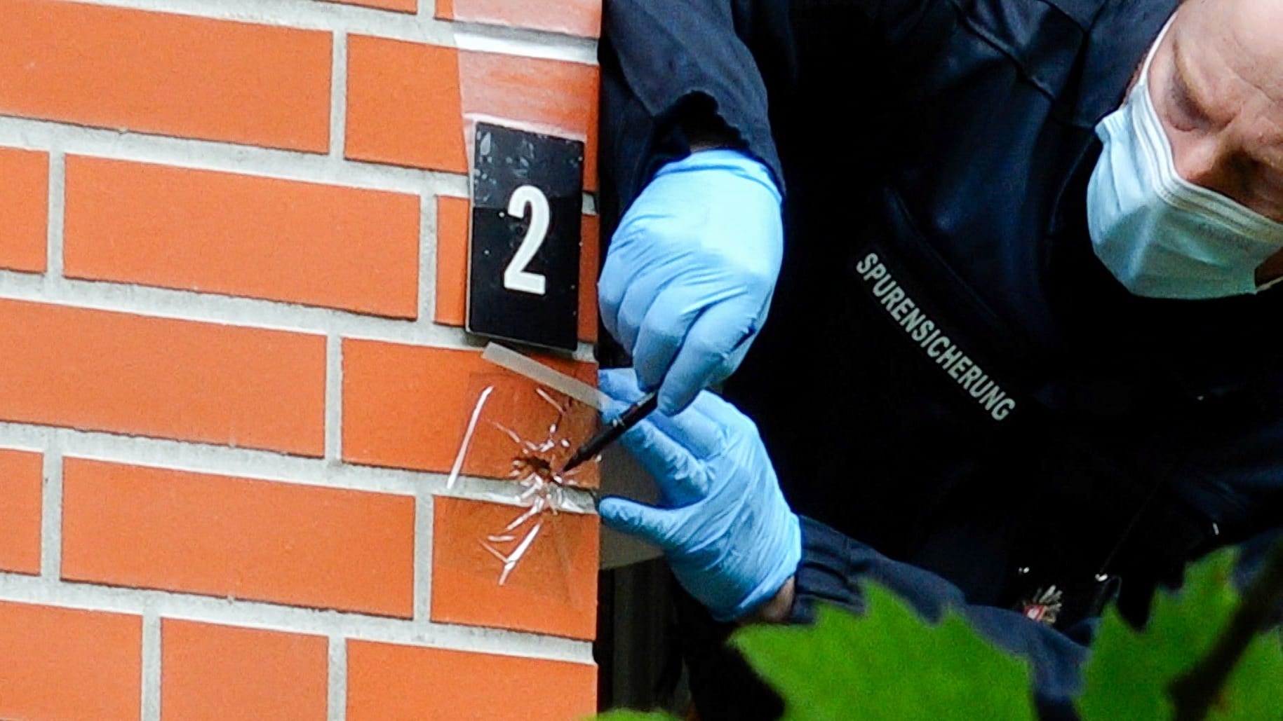 Ein Beamter untersucht ein Einschussloch neben einem Balkon: Noch ist unklar, wer wie oft und mit welchen Waffen geschossen hat.