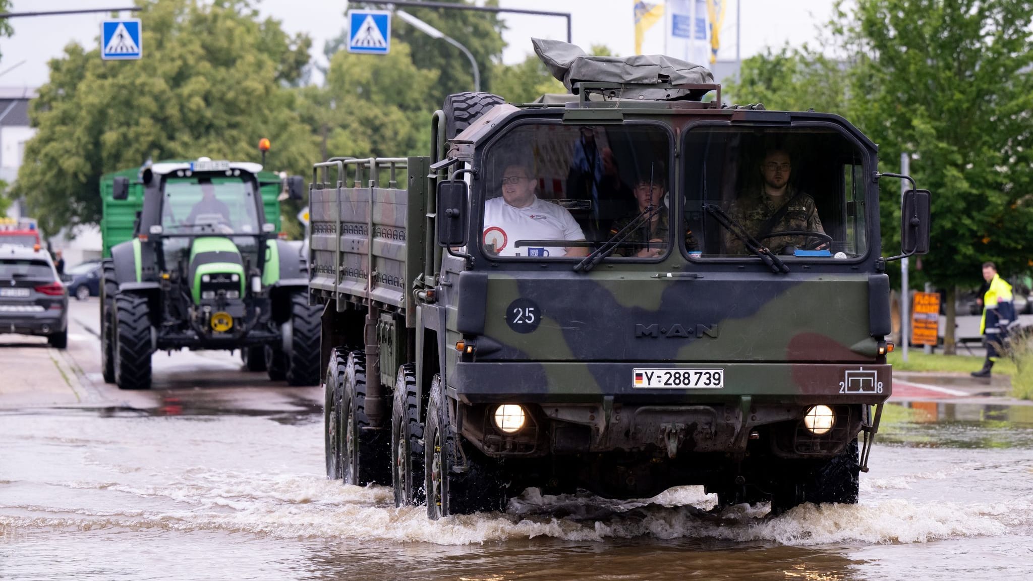 Bayern, Reichertshofen: Helfer und Soldaten fahren über eine überflutete Straße.