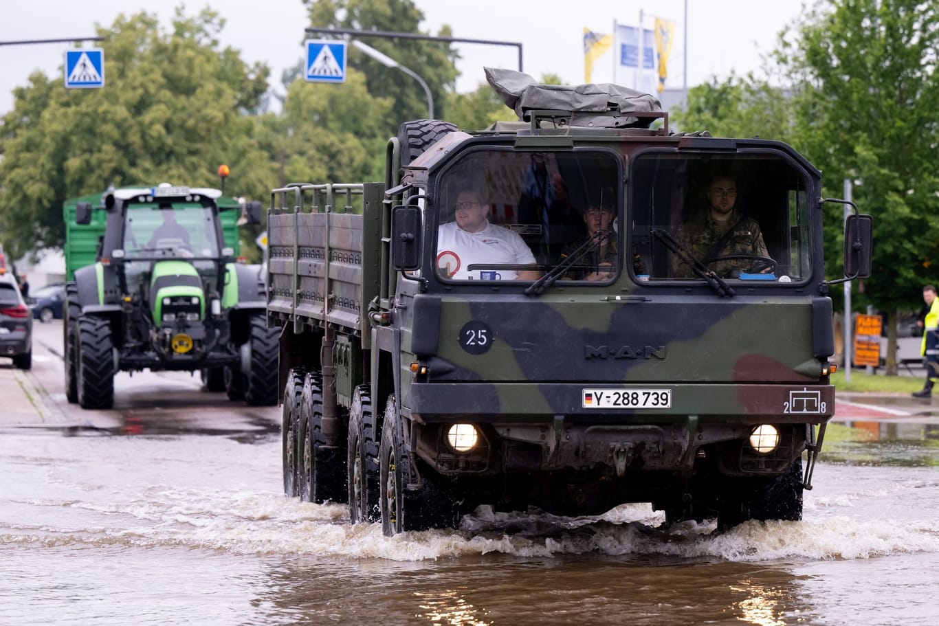 Bayern, Reichertshofen: Helfer und Soldaten fahren über eine überflutete Straße.