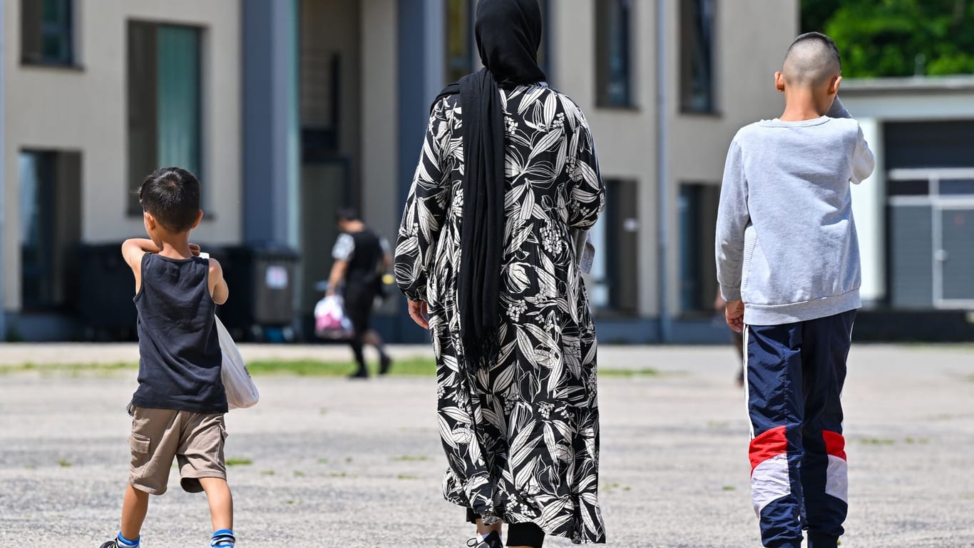 Eine Migrantin und ihre zwei Kinder gehen über das Gelände der Zentralen Erstaufnahmeeinrichtung für Asylbewerber des Landes Brandenburg (Symbolbild): Die Ministerpräsidentenkonferenz hat einen Asyl-Beschluss gefasst,