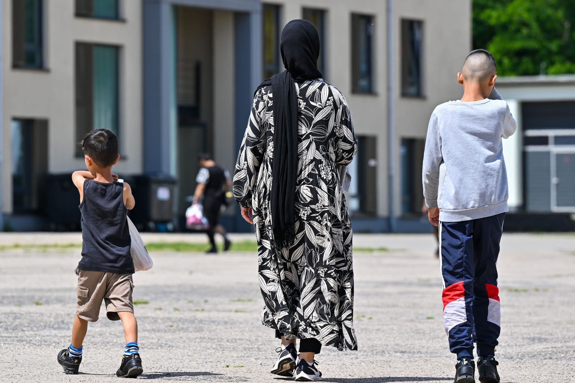 Eine Migrantin und ihre zwei Kinder gehen über das Gelände der Zentralen Erstaufnahmeeinrichtung für Asylbewerber des Landes Brandenburg (Symbolbild): Die Ministerpräsidentenkonferenz hat einen Asyl-Beschluss gefasst,