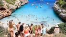 Menschen stehen Schlange am Strand Calo des Moro in Mallorca (Archivbild): Der Massentourismus zerstört die Natur vor Ort.