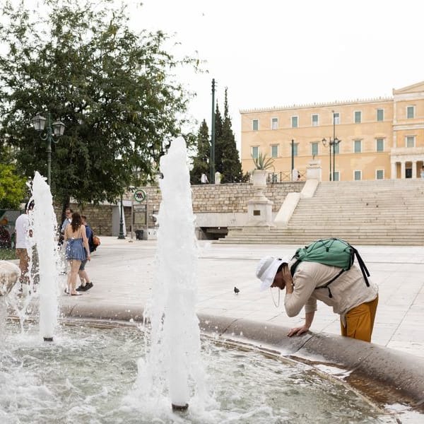 Ein Mann erfrischt sich an einem Springbrunnen auf dem Athener Syntagma-Platz.