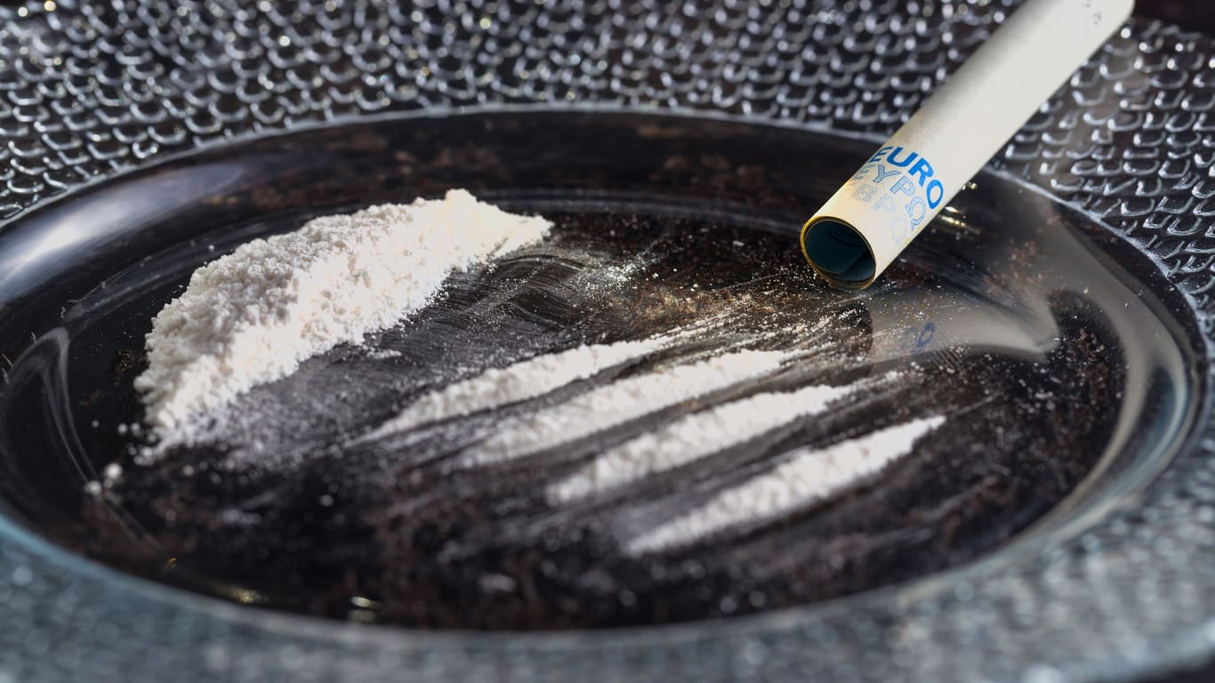 Cocaine drug addiction. Four lines of cocaine and a 20 Euro bill rolled into a tube are on a plate prepared for use. Drugs.