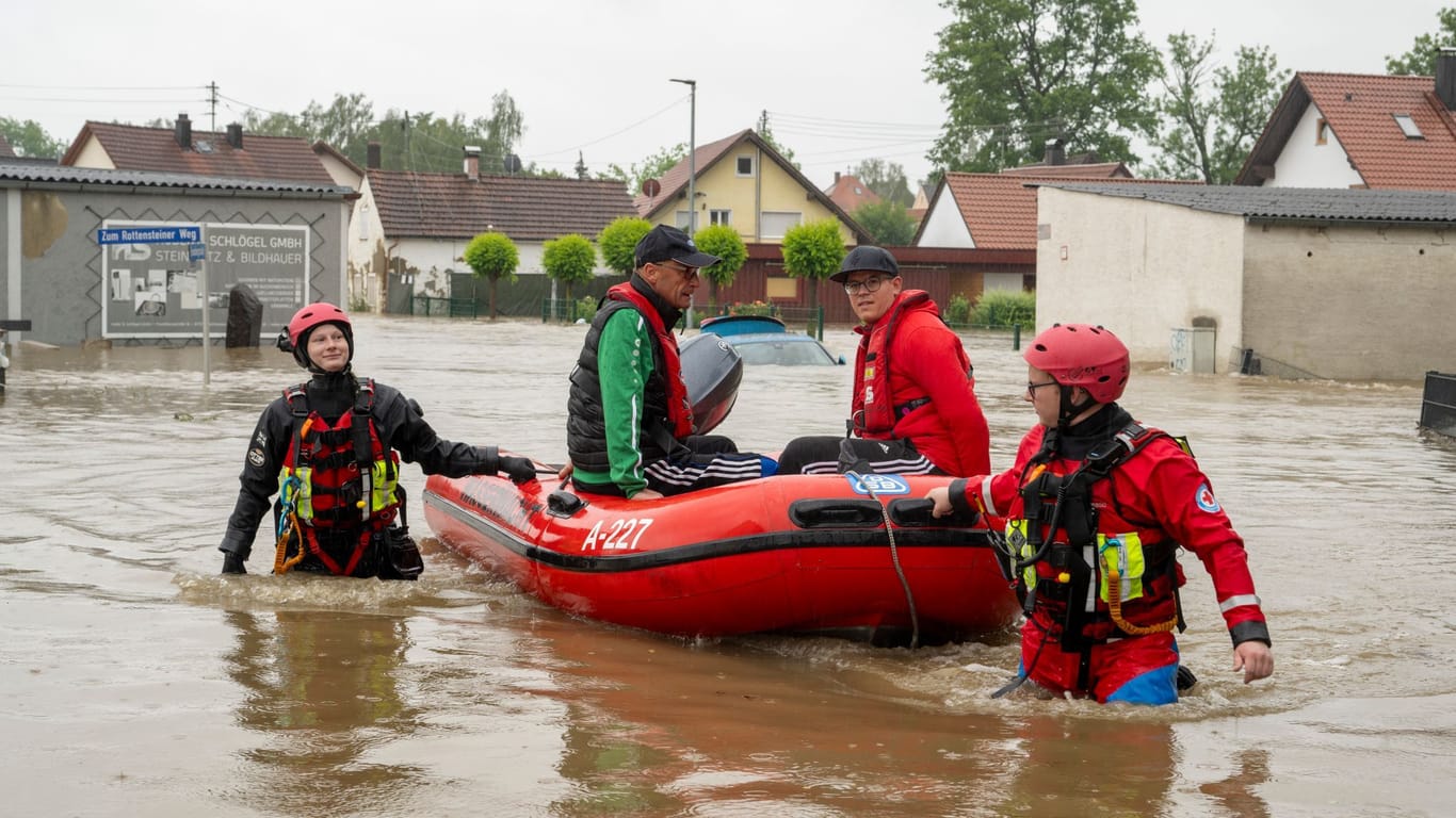 Wasserretter bergen Bewohner aus einem überschwemmten Haus.