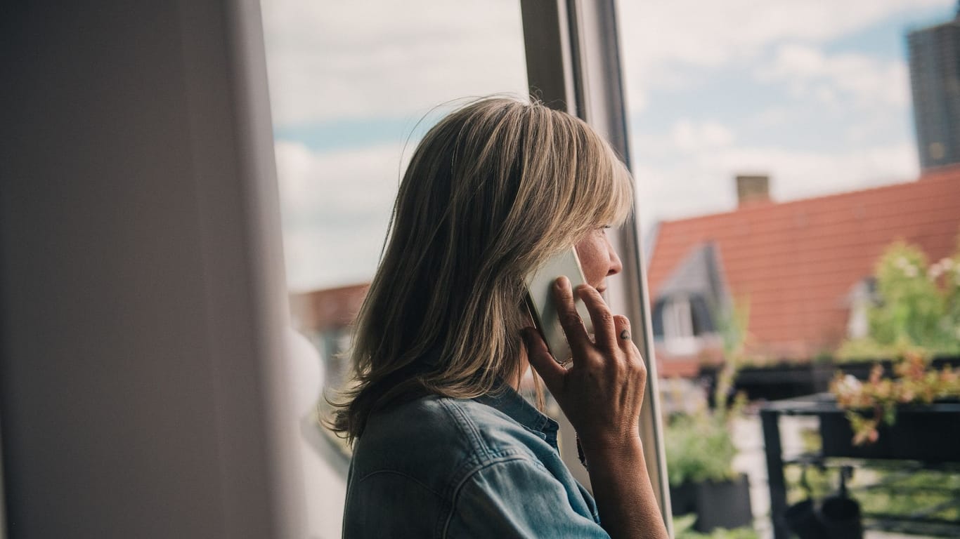 Eine Frau telefoniert am Fenster