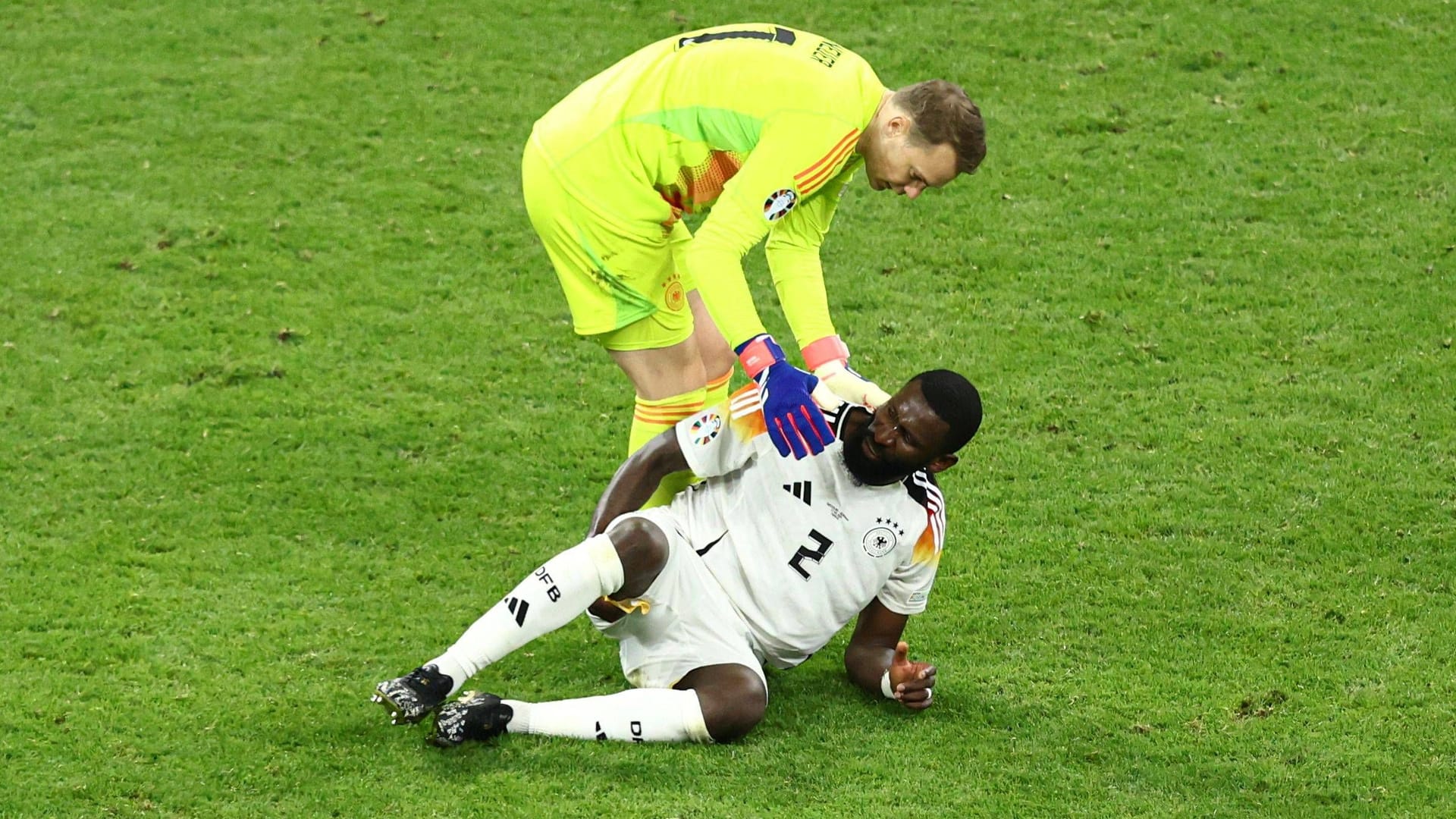 Manuel Neuer hilft Antonio Rüdiger auf.